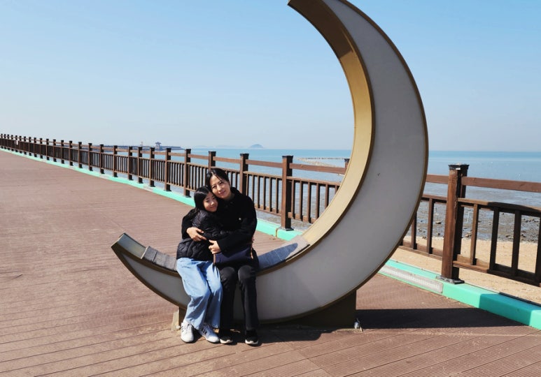 바다가 보이는 달 모양 벤치에 서로 안고 앉아 있는 재키쌤과 딸 이안이